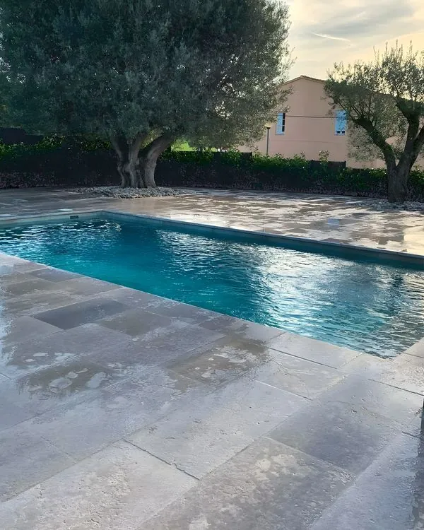 Piscina con playa de piedra y olivos · Instagram @morales_obresiserveis